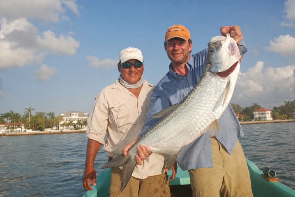 Captain Tayo Verde holding a large tarpon with a fishing guest
